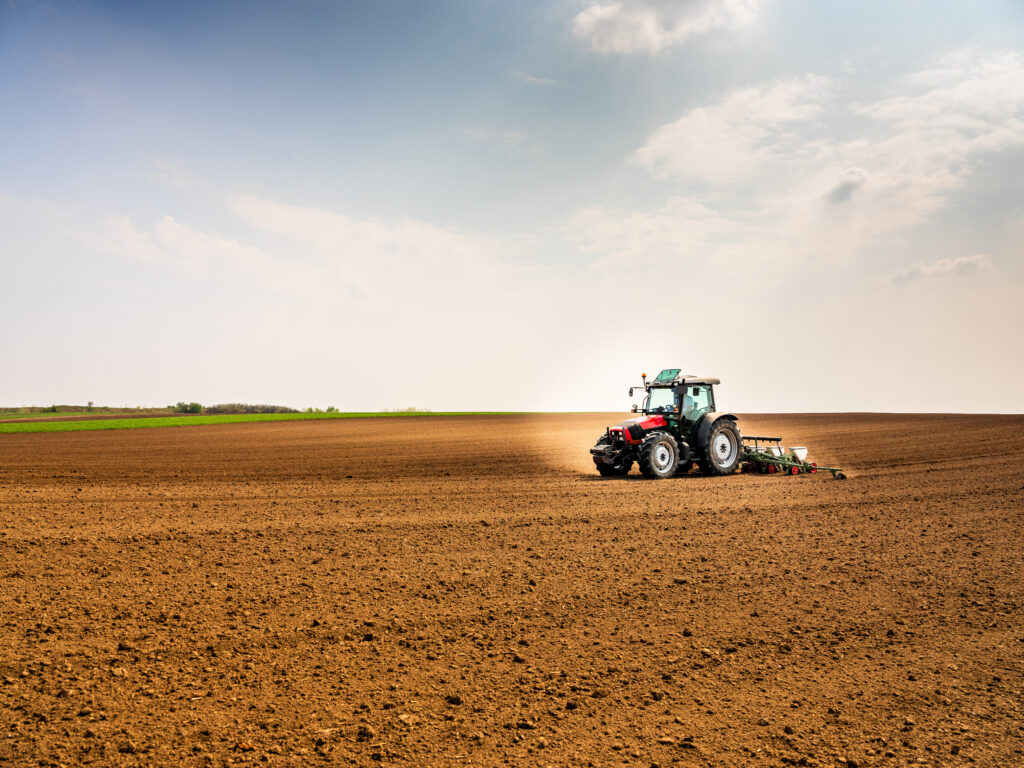 Tracteur en train de semer des cultures dans un champ agricole. Activité agricole