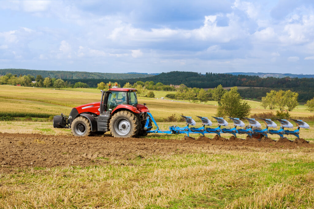 Un tracteur équipé d'une grande charrue laboure un champ. Tracteur avec outil agricole.